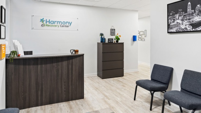 Interior reception area featuring Harmony Recovery Center logo on wall, dark wood desk, seating, and decorative elements