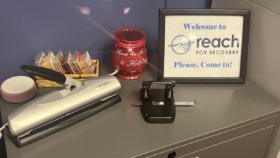Interior reception desk with welcome signage for Reach for Recovery, office supplies, and decorative items