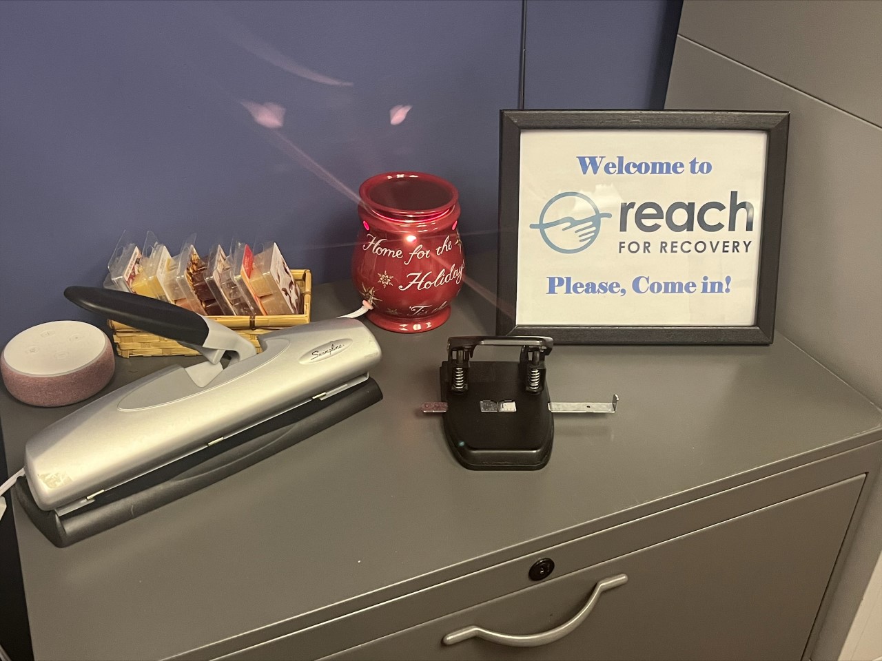 Interior reception desk with welcome signage for Reach for Recovery, office supplies, and decorative items