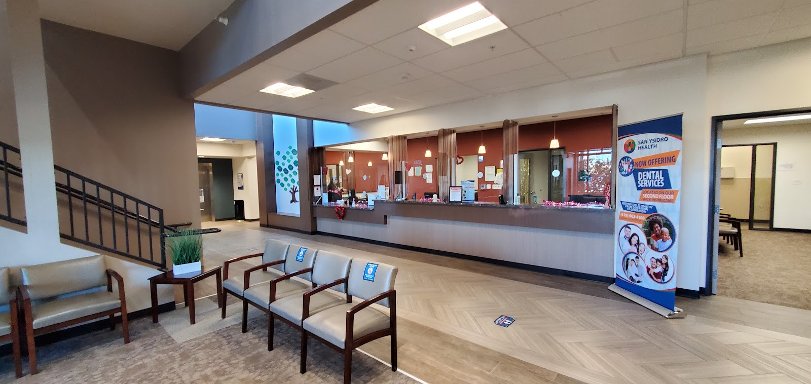 Interior reception area with curved service desk, patient seating, and climbing plant feature wall