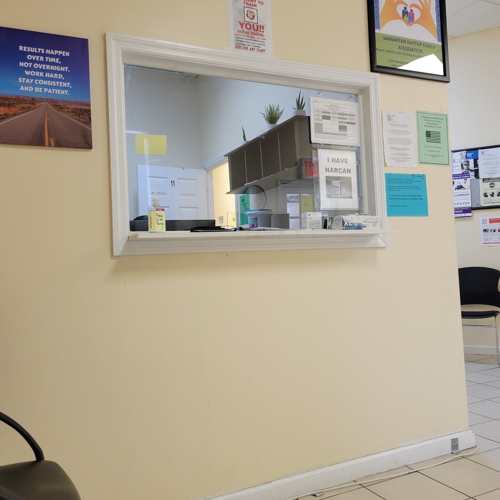 Interior reception service window showing office equipment, plants, and patient check-in area with motivational wall signage