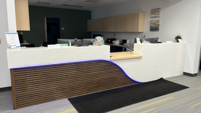 Interior reception desk with white counter, dual computer stations, green accent wall, and modern lobby furnishings