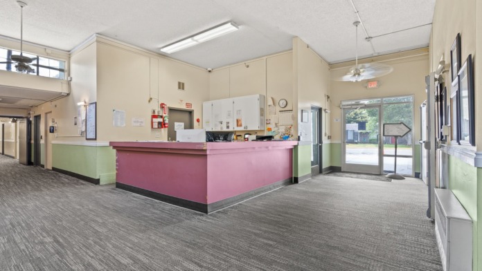 Interior reception area with pink desk, cream walls with green wainscoting, exit signage, and glass entry doors