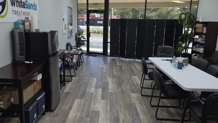 Interior reception space with WhiteSands Treatment signage, front desk, seating area, and large windows overlooking grounds