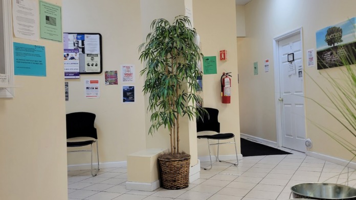 Interior reception lobby with comfortable seating, informational posters, plants, and service window