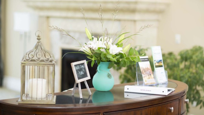 Interior reception area showing wooden desk with decorative floral arrangement, birdcage, and welcome signage