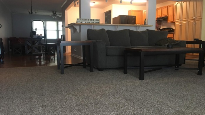 Interior recreation space with dark sofas, coffee table, motivational wall signage, and open floor plan layout