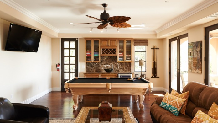 Interior recreation lounge featuring pool table, brown leather seating, flat-screen TV, decorative mirrors, and entertainment amenities