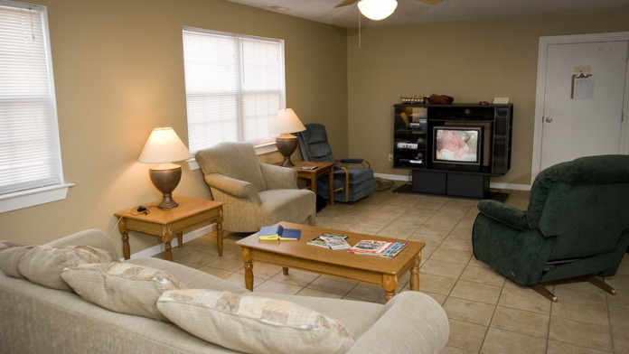 Interior recreation area with comfortable seating, wooden coffee table, television, and natural lighting
