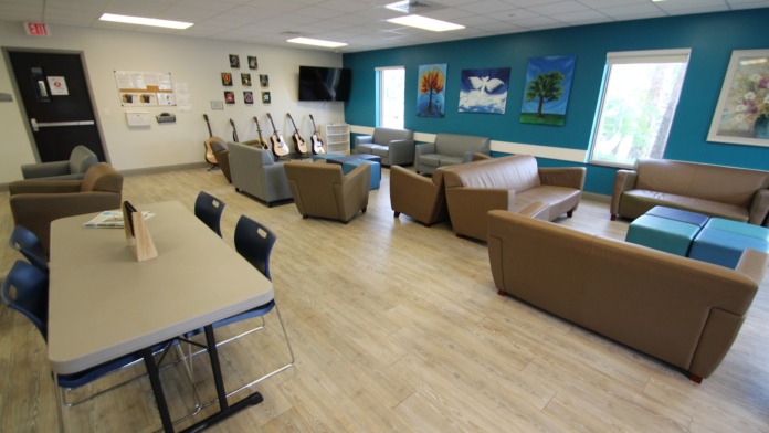 Interior common lounge with guitars on wall display, turquoise painted walls, various seating options, artwork, television, and entertainment amenities