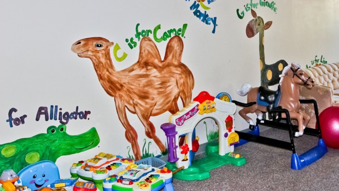 Interior activity room with colorful teaching animals mural, interactive learning toys, exercise equipment, and ball pit