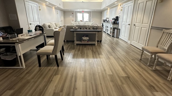 Interior hallway view showing open layout with seating areas, kitchen, and multiple doorways in neutral tones