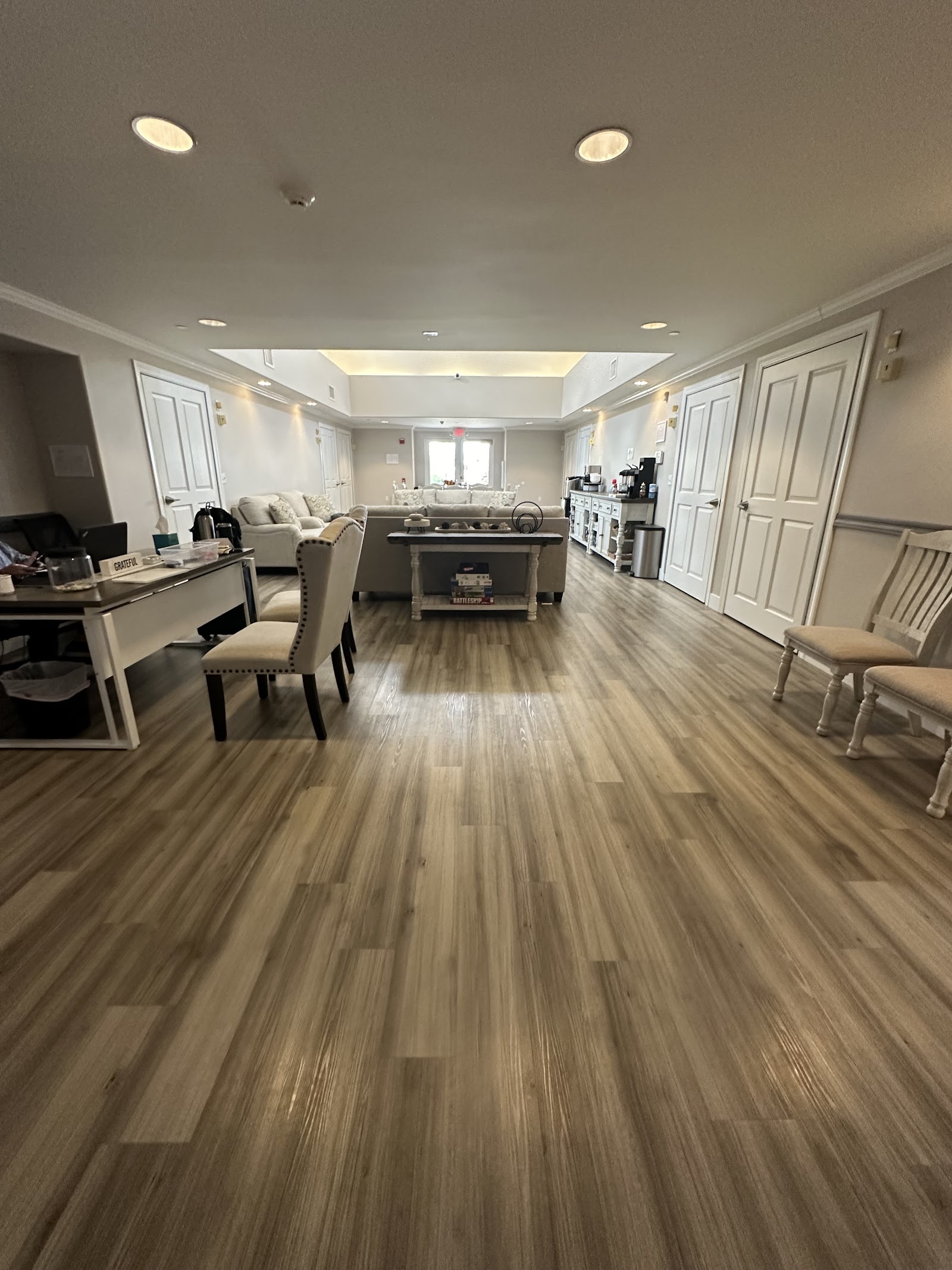 Interior hallway view showing open layout with seating areas, kitchen, and multiple doorways in neutral tones