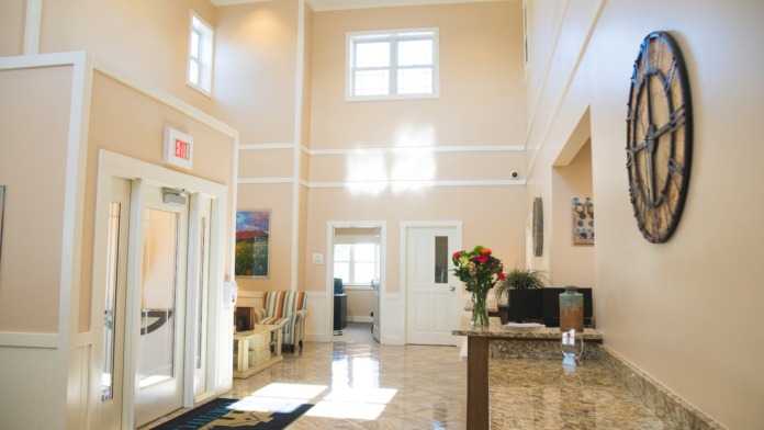 Interior multi-bed dormitory with wooden beds, turquoise bedding, bulletin boards, windows, and storage