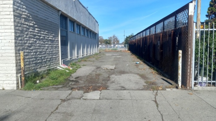 Exterior view showing facility side building, fenced courtyard area, and perimeter security fencing