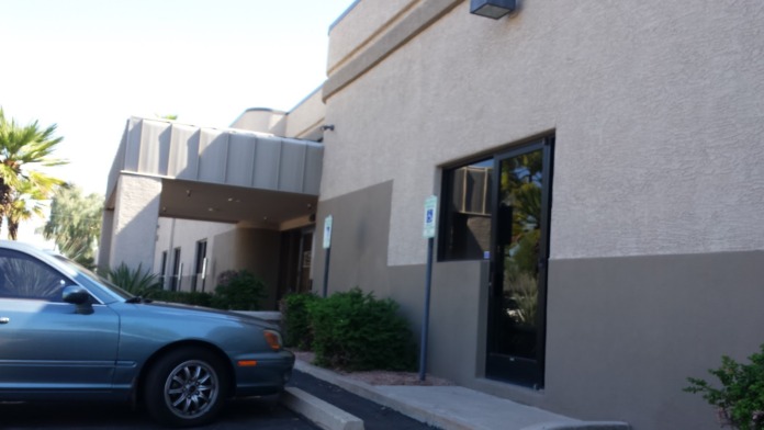 Exterior side entrance showing facility entrance door with canopy overhang and parked vehicle