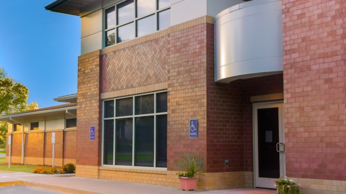 Exterior side entrance with brick facade, accessible parking signs, landscaping, and modern building design