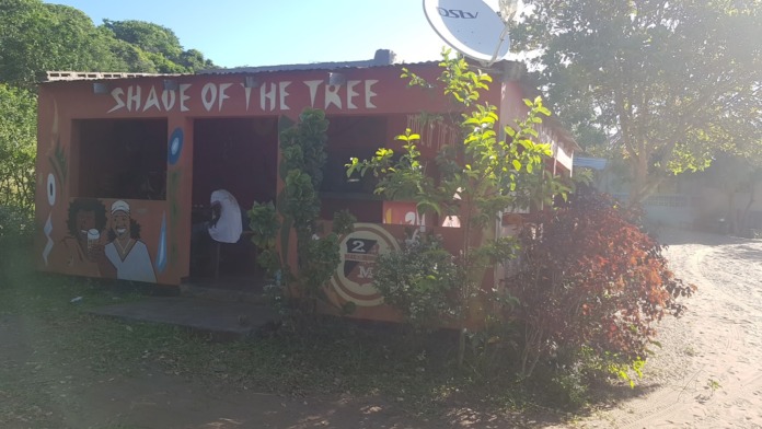 Exterior side view of red facility building with painted artwork, green vegetation, and satellite dish visible