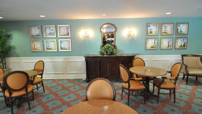 Interior intimate seating area with two orange upholstered club chairs, small decorative table, lamp, and window with floral curtains