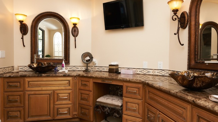 Interior bathroom with dual sink vanity, decorative mirrors, wall sconces, granite countertops, and spa-style finishes