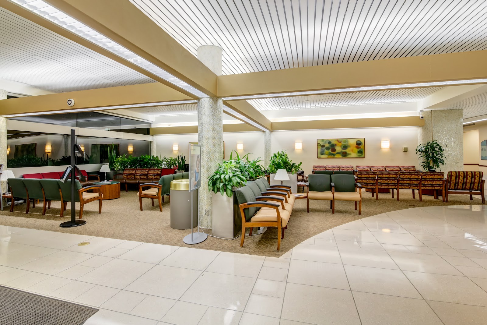 Interior common area with multiple seating zones, planted decorations, vaulted ceiling with skylighting and open floor layout