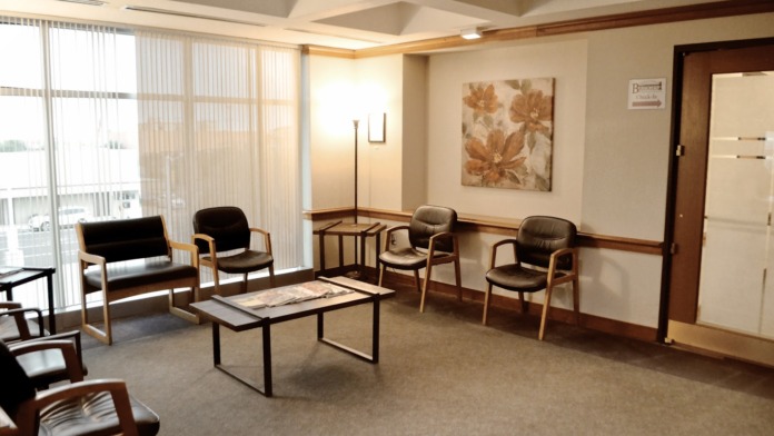 Interior lounge with multiple seating areas, coffee table, artwork, and large windows providing natural light