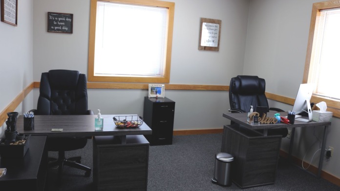 Interior office space with two desks, chairs, windows, and motivational signage on walls