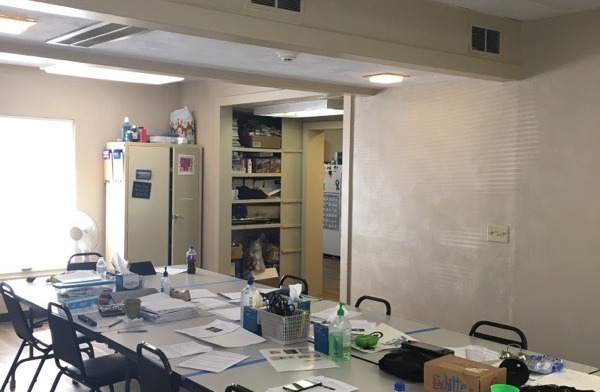 Interior office space with work tables, chairs, storage cabinets, and administrative workspace