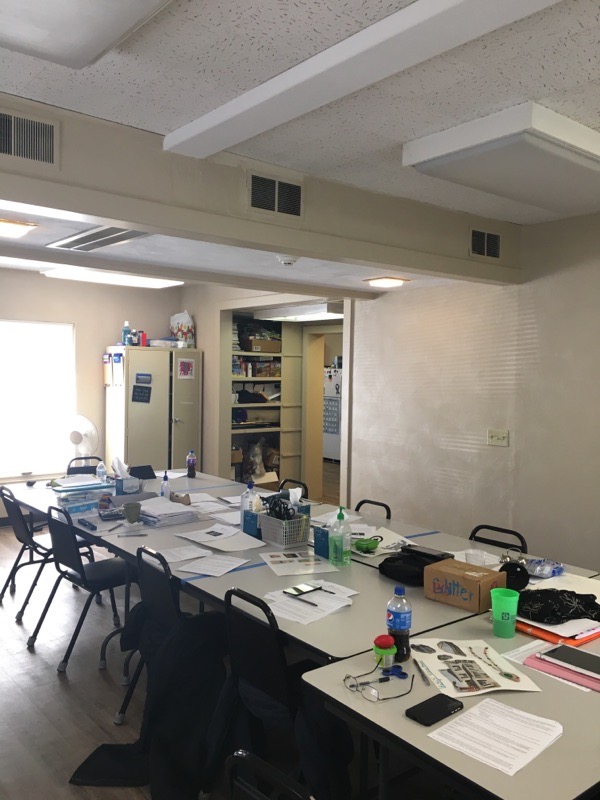 Interior office space with work tables, chairs, storage cabinets, and administrative workspace