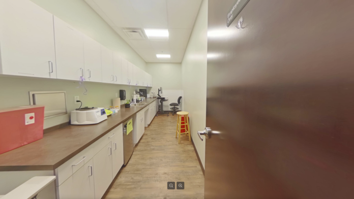 Interior staff area with long counter, white cabinets, coffee station, red bin, and yellow stool