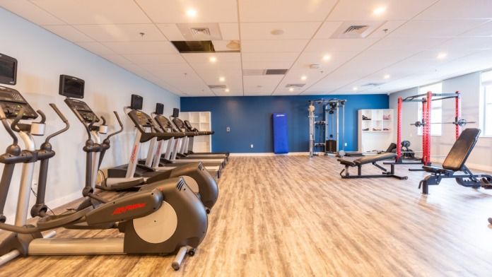 Interior fitness facility with cardio equipment, strength training machines, and workout area with blue accent wall