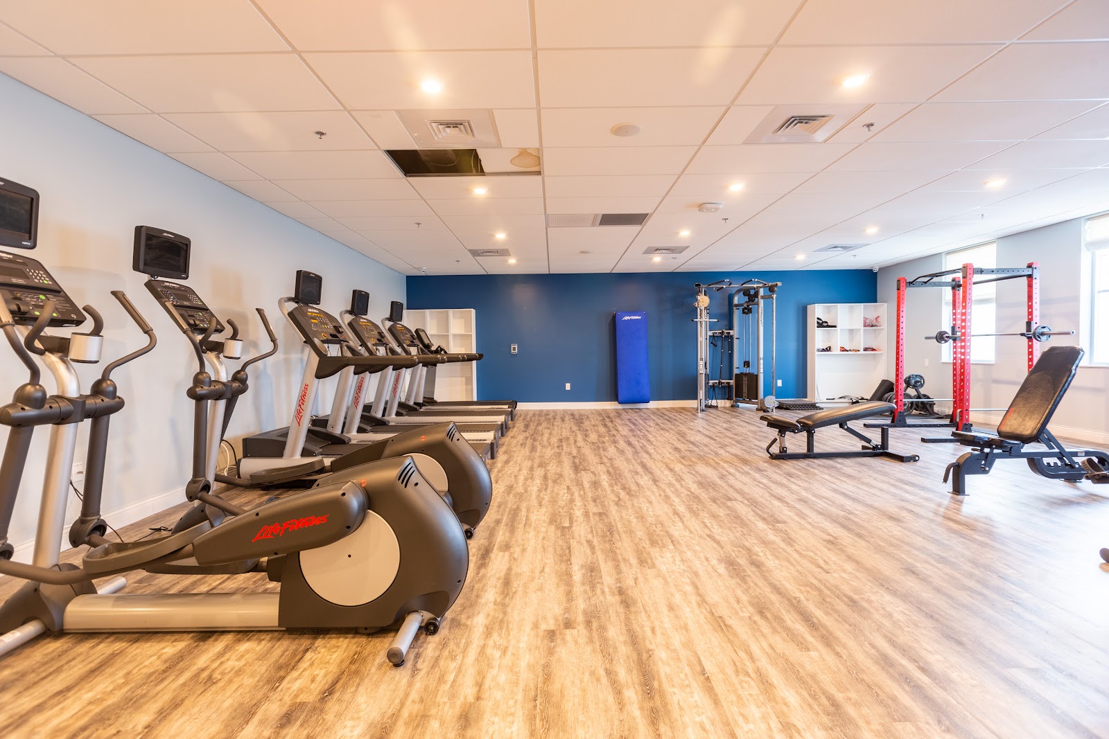Interior fitness facility with cardio equipment, strength training machines, and workout area with blue accent wall