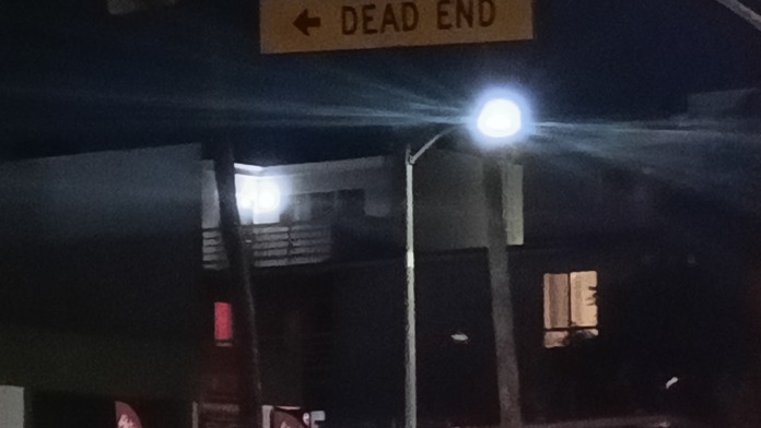 Exterior nighttime street view showing Beachwood Drive sign and dead end marker with traffic light and building facade