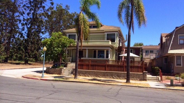 Exterior street view of treatment facility showing full two-story building facade with palm trees and neighboring residential properties