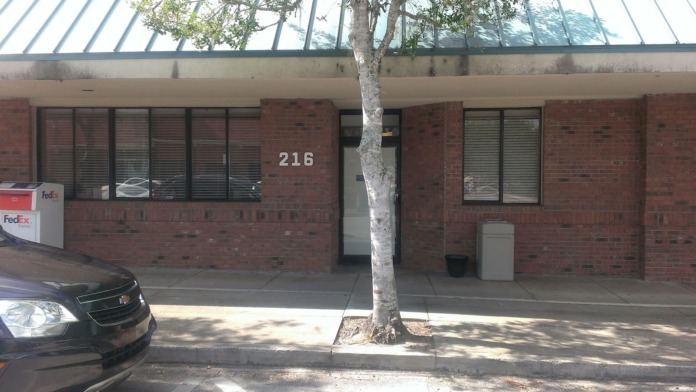 Exterior view of facility address 216 with brick construction, green awning, windows with blinds, and adjacent parking