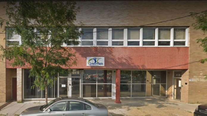 Exterior brick storefront showing CenterPath Wellness signage, large windows, and street-level entry with parked car