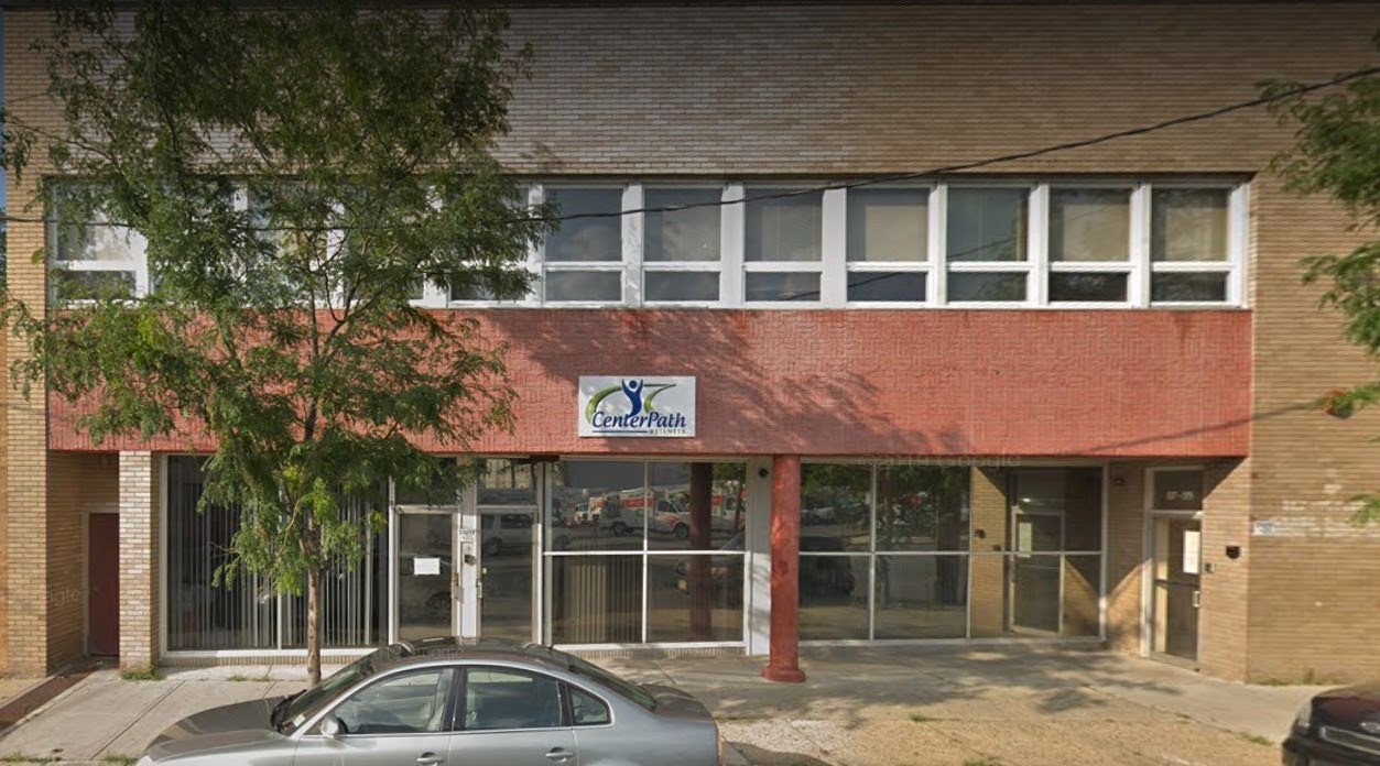 Exterior brick storefront showing CenterPath Wellness signage, large windows, and street-level entry with parked car