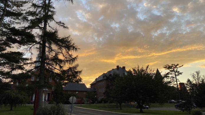 Exterior sunset view of facility campus with mature trees, buildings, and manicured grounds