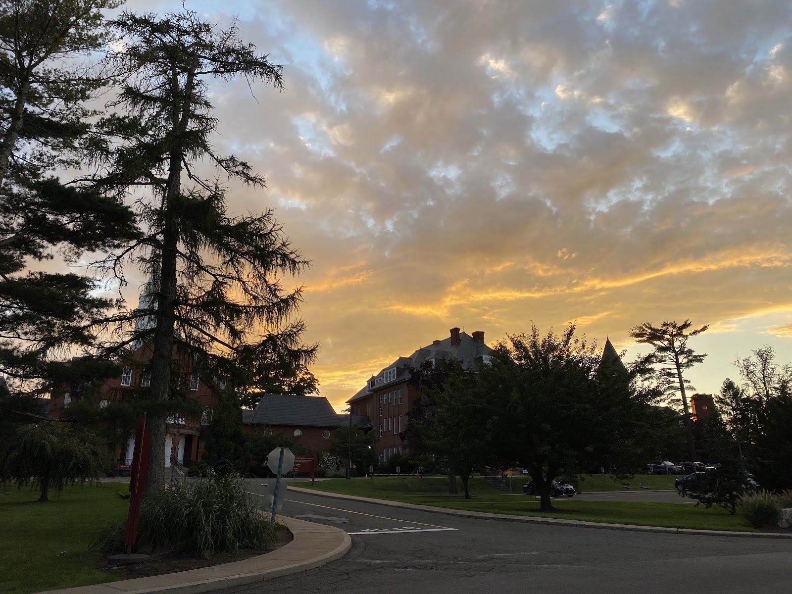Exterior sunset view of facility campus with mature trees, buildings, and manicured grounds