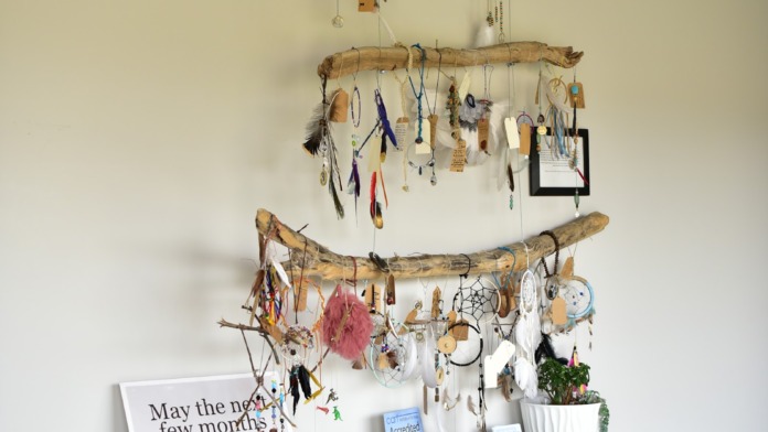 Interior wall with multiple hanging dreamcatchers and decorative pieces on driftwood with affirmation signage.