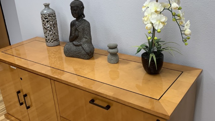 Interior office space with wooden furniture, decorative Buddha statue, white orchid plant, and calm aesthetic design elements