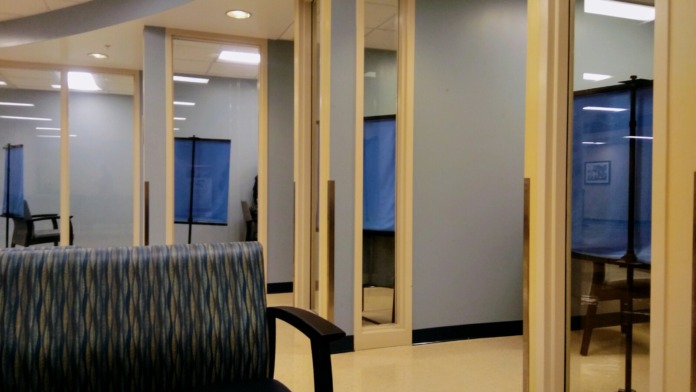 Interior clinical space with glass-enclosed examination rooms and modern medical treatment equipment