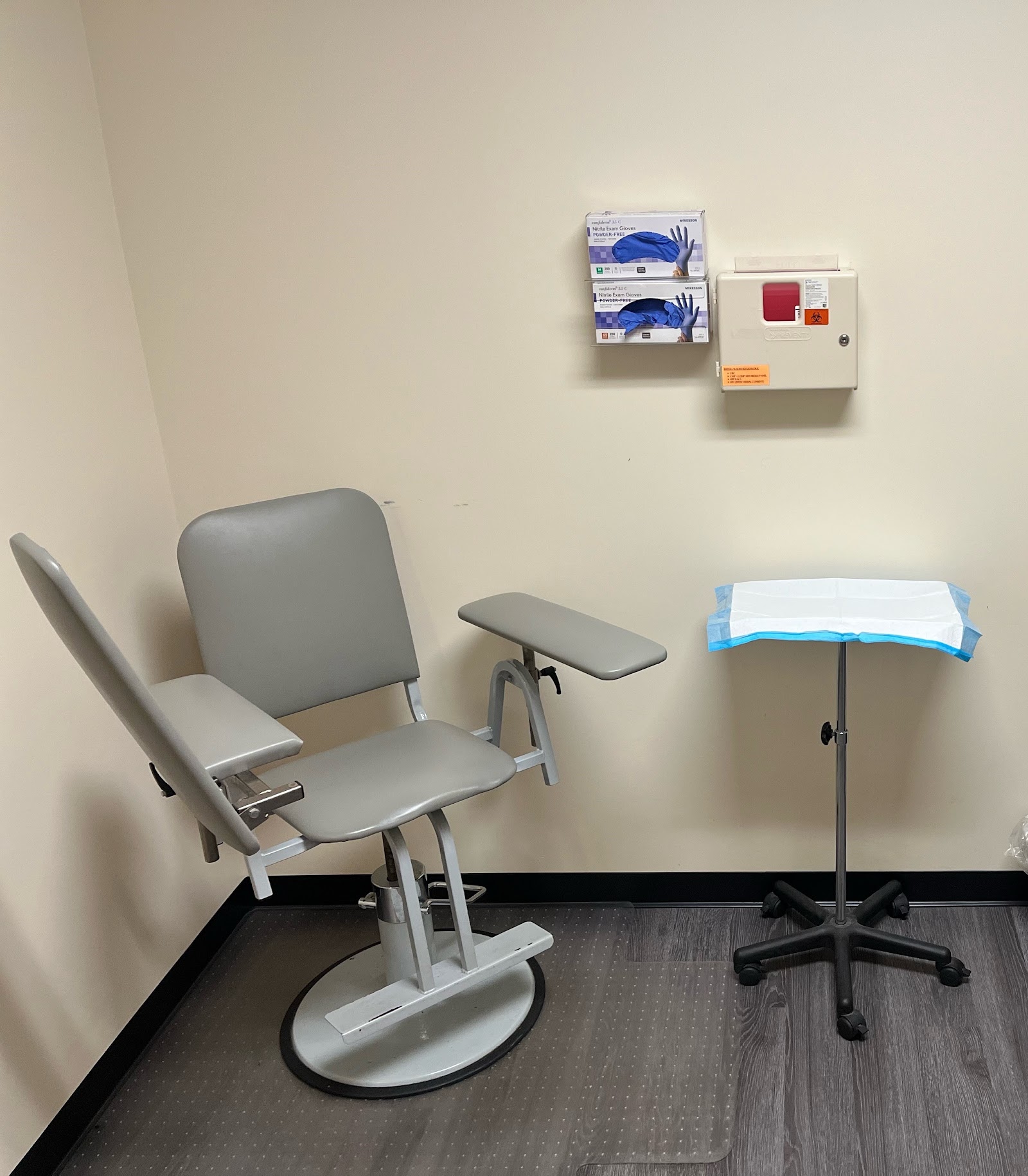 Interior treatment room with medical examination chair, supply dispensers, and standard medical furniture