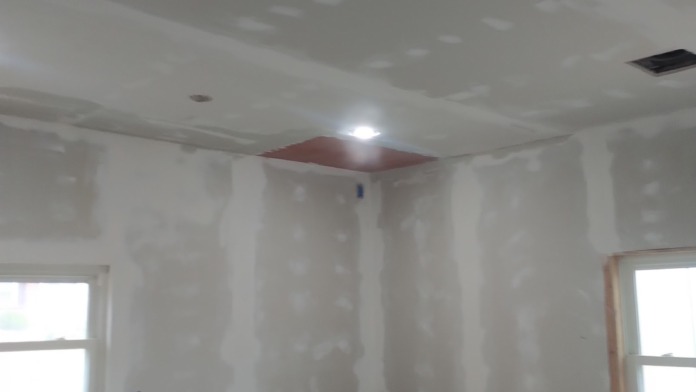 Interior treatment space under construction with drywall finish, recessed lighting, brick wall detail, and windows