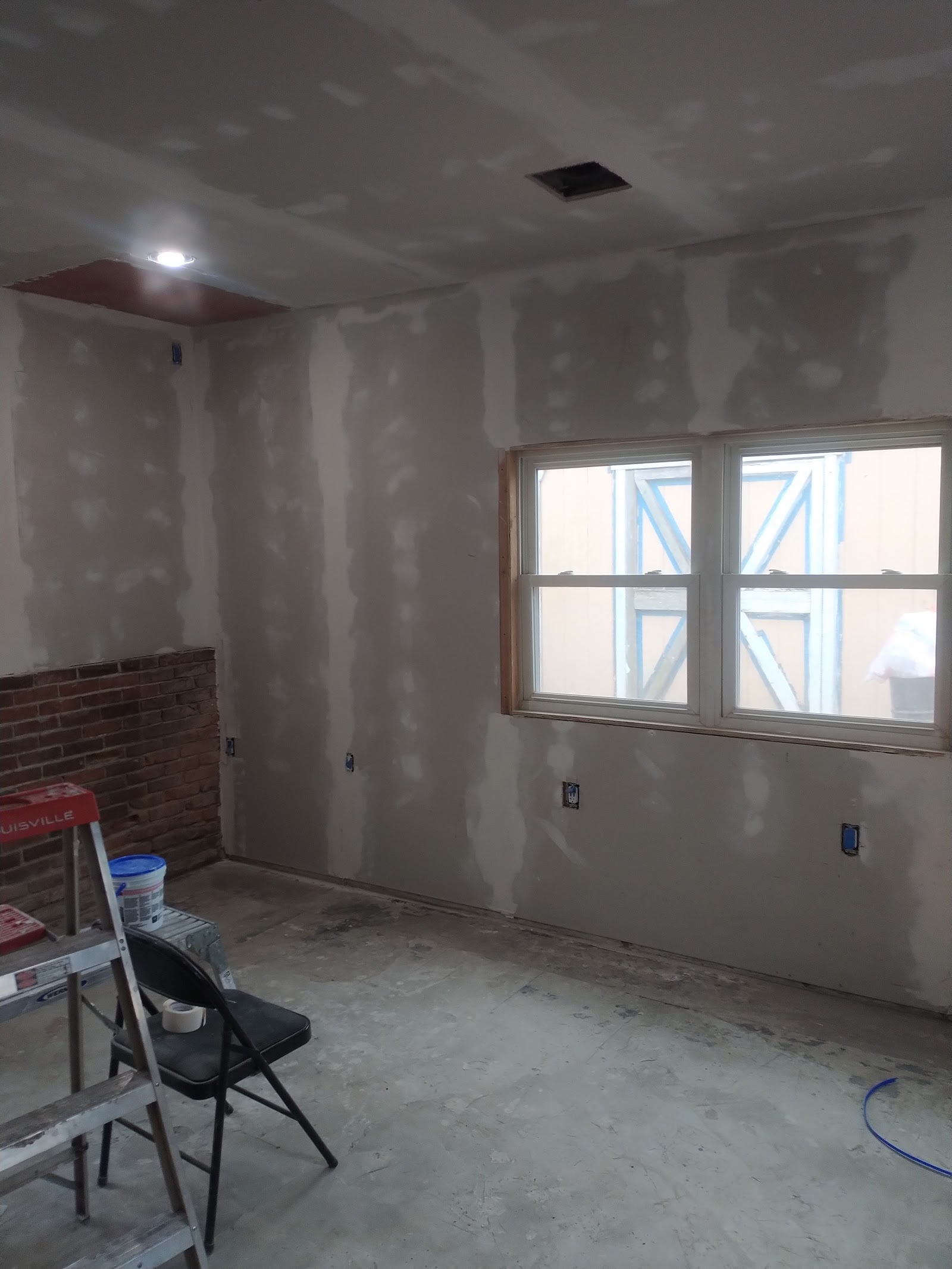 Interior treatment room under renovation with drywall, window with construction tape, and electrical outlets