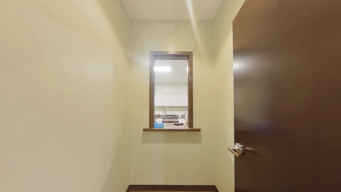 Interior hallway with cream walls, brown trim, mounted display, brown doors, and seating chairs