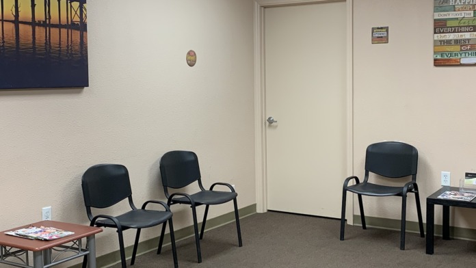 Interior lounge space with black chairs, small tables with magazines, inspirational wall posters, and office door