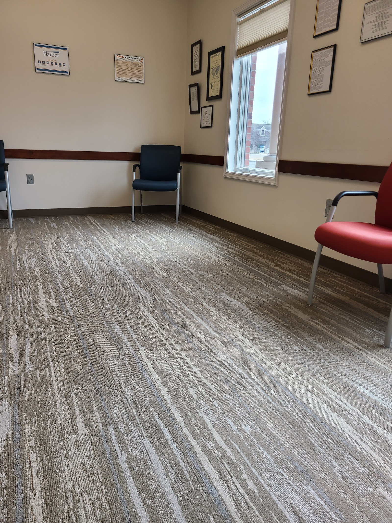 Interior waiting room with comfortable seating, windows, and patient information displayed on walls