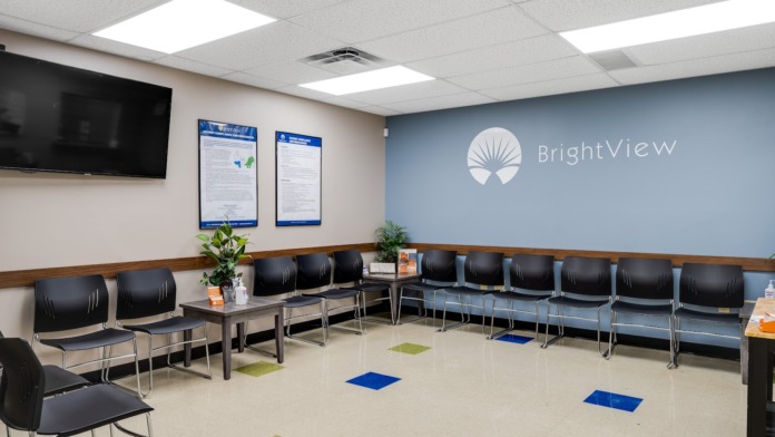 Interior waiting room with rows of seating, BrightView signage, information displays, and plants