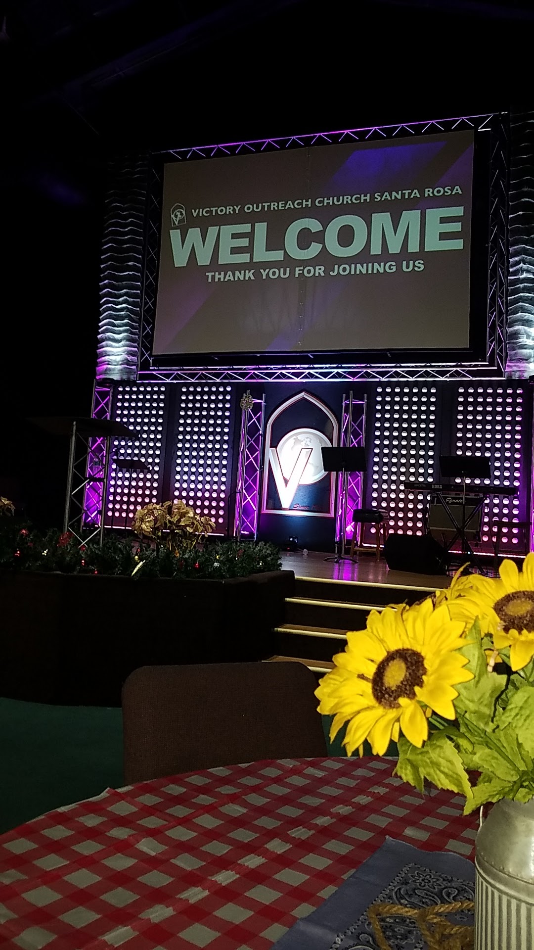 Interior stage with purple and teal lighting, welcome signage, and professional event setup